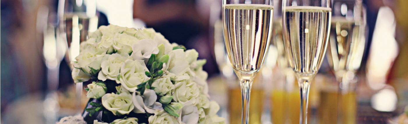 White rose bouquet beside champagne glasses